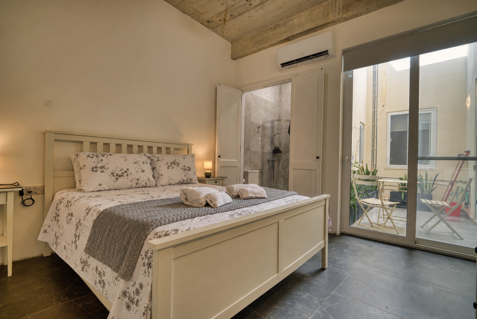 Double bedroom with a grey headboard, white linen and two bedside lamps